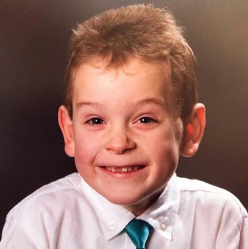 young boy with front tooth missing and cyan tie and white shirt