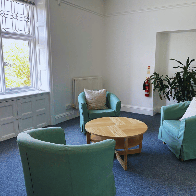 white room with blue chairs and a coffe table in the middle
