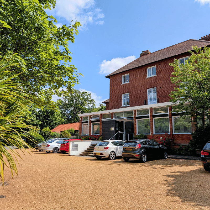 Sunny day showing the front of the help for psychology building with cars parked out the front